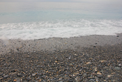 Rocks on the beach with a wave washing in.