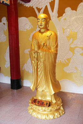 Another Buddhist statue looking devout with clasped hands.