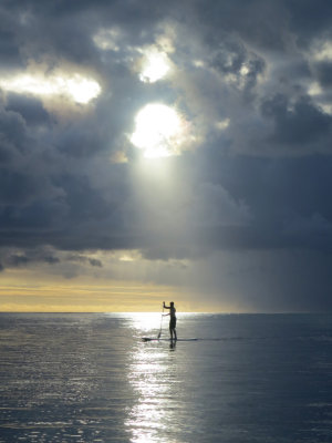 stand up paddling into the sunset