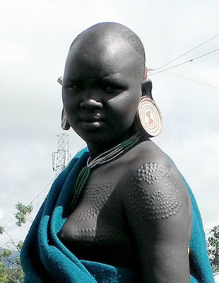 Surma girl with scarification marks and big ear plates;  south-western Ethiopia.