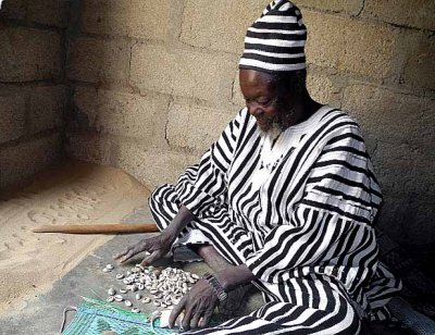 Healer Ba Zane (Mossi tribe) in Sena, Burkina Faso, writes magic words in the sand and throws cowries to help his clients.