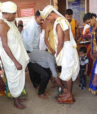 Wedding ceremony in Karnataka, India; a member of the brides family washes the grooms feet