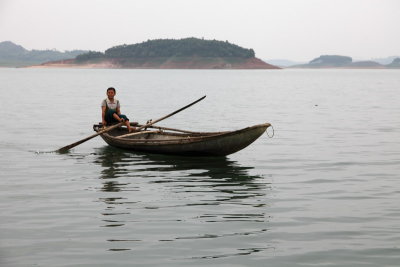 Femme pchant sur le lac Thac Ba