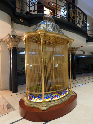 A bird cage in the foyer full of birds