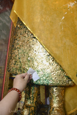 Paying merit to Buddha by applying a gold foil paper!