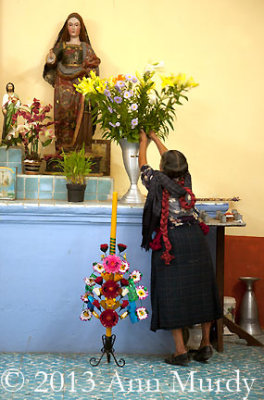 Macaria adding flowers to the altar
