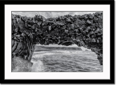 Arch out of basaltic rocks carved by waves