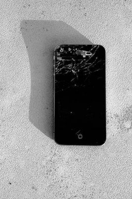 Dead iPhone atop a telephone utility box by the sidewalk