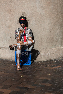 Aboriginal street performer on his smart phone