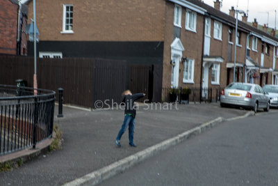 Boy throwing stones at Peace Wall, Belfast