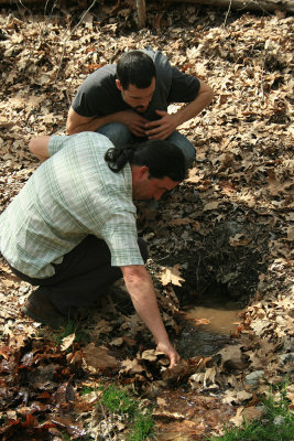 Alex watches as Andrew clears out the mouth of the spring