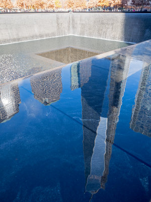 9/11 Memorial with the One World Trade Center building in the reflection.