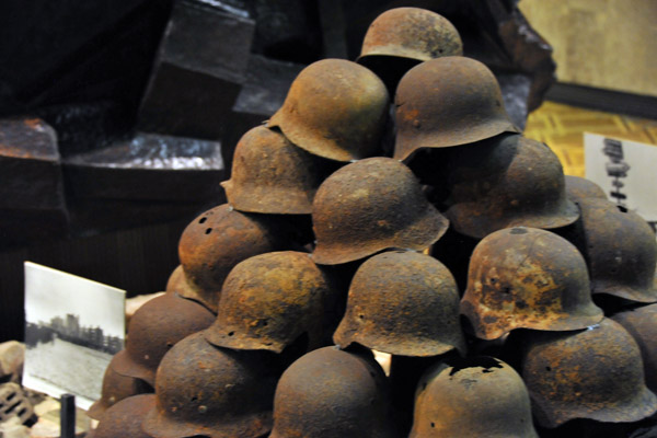 Rusting German steel helmets stacked on top of rubble