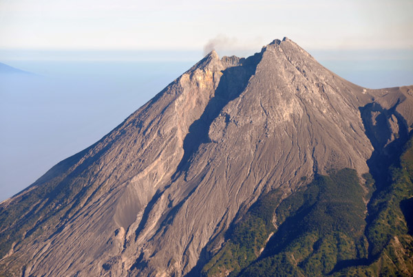 A wisp of smoke rises from the lip of Mt. Merapi