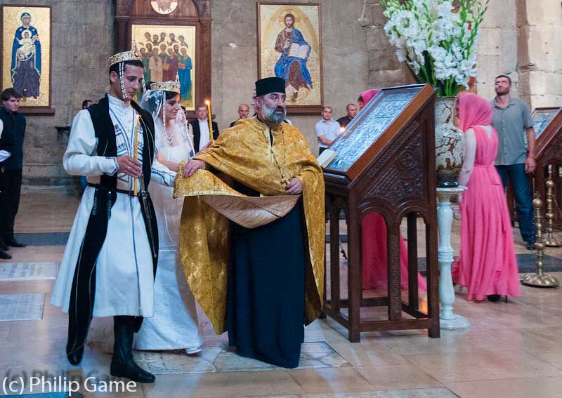 The priest conducts bride and groom...