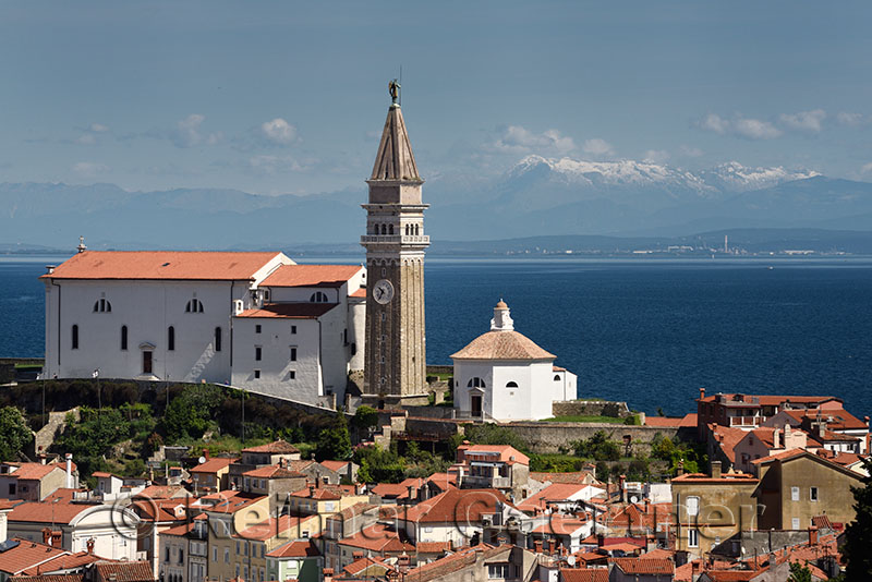 Piran Slovenia with St Georges Cathedral belfry and baptistery on the Gulf of Trieste with snow capped Kanin mountains and dist
