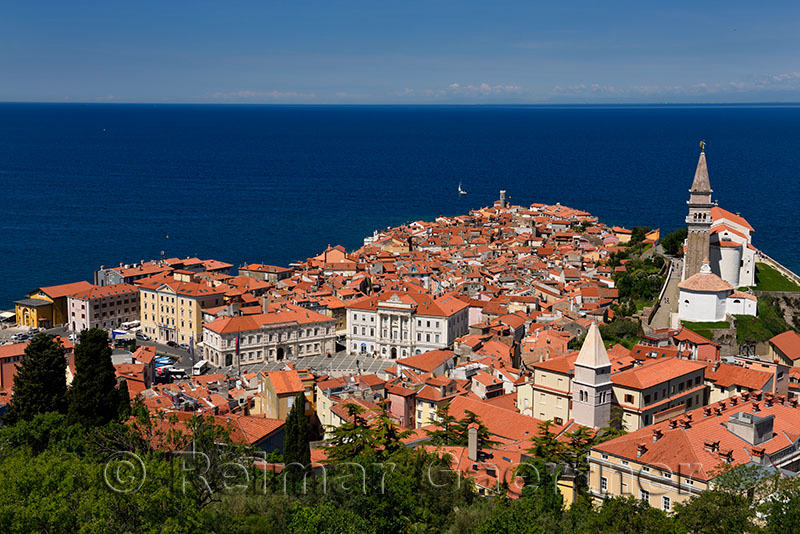 Cape Madonna at Point of Piran Slovenia on blue Adriatic Sea with Tartini Square courthouse City Hall and St Georges Catholic c