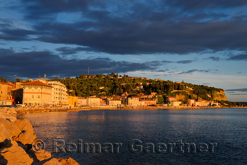 Red light at sunset on the Adriatic Sea coast at Piran Slovenia harbor and hill overlooking old town