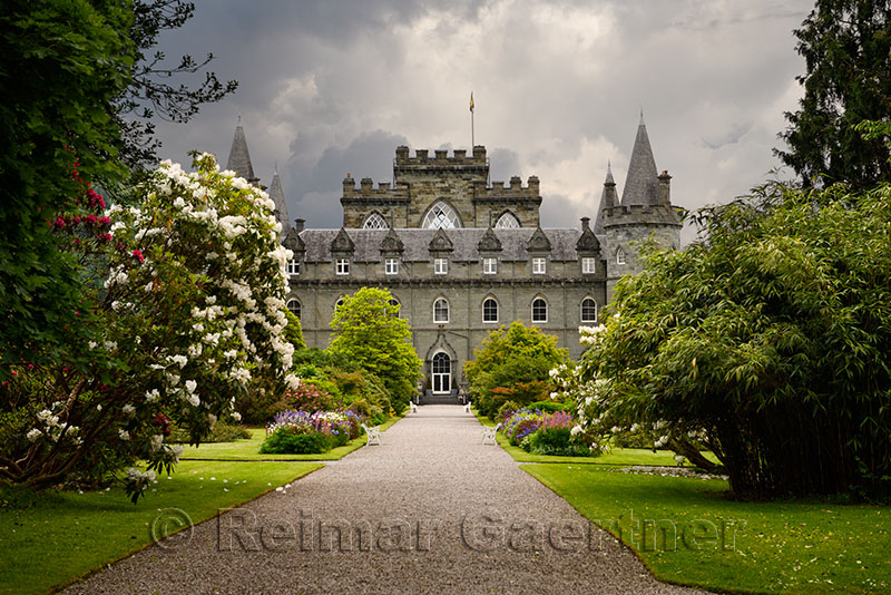 Turreted Inveraray Castle in Gothic Revival style from the flower gardens with dark clouds in the Scottish Highlands Scotland UK