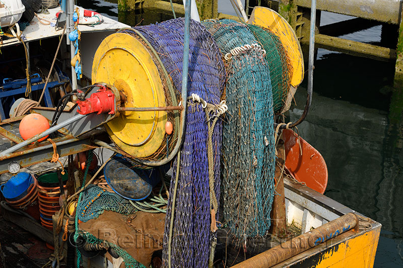 Colorful net on a reel at stern of a commercial trawler fishing boat in Oban harbour Scotland UK