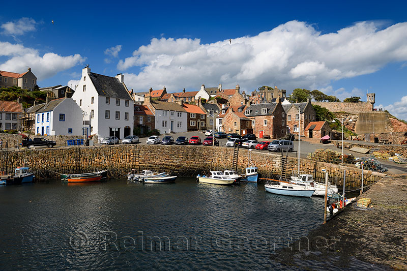 Stone ramp and pier walls at Crail Harbour with fishing boats and lobster traps in Crail Fife Scotland UK