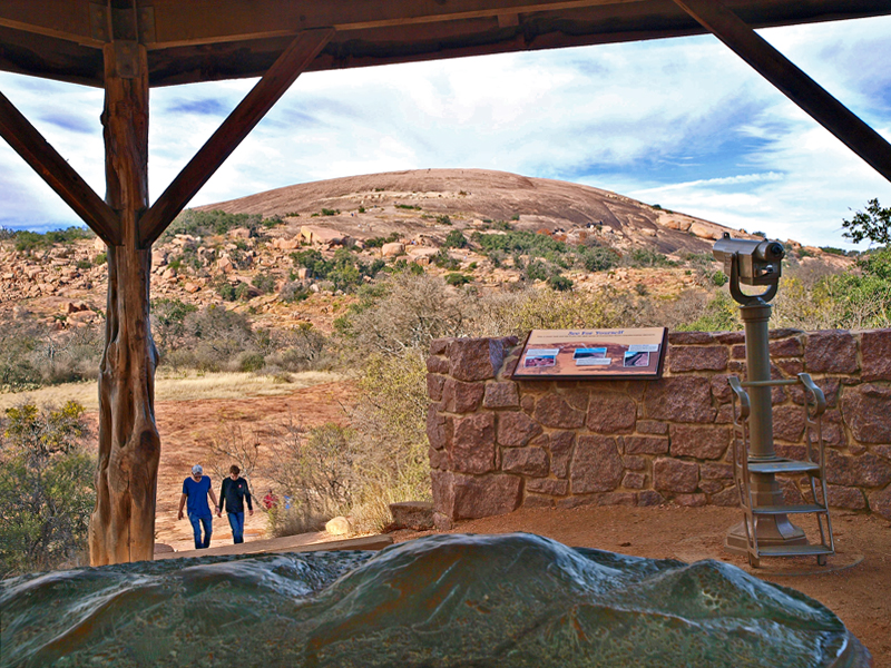 Hikers returning from Summit Trail, with rock in background and bronz sculpture of rock in foreground