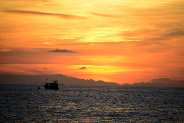 Sunrise with a fishing boat and the Thai mainland