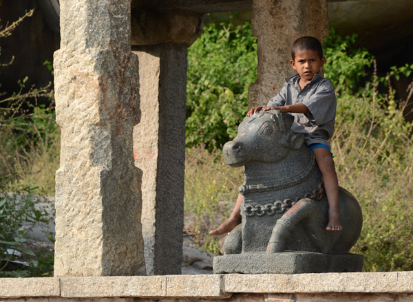 Young boy riding a small sculpture of the sacred bull Nandi