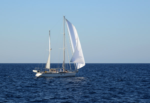 Sailboat flying his spinnaker heading around the Revellata Peninsula