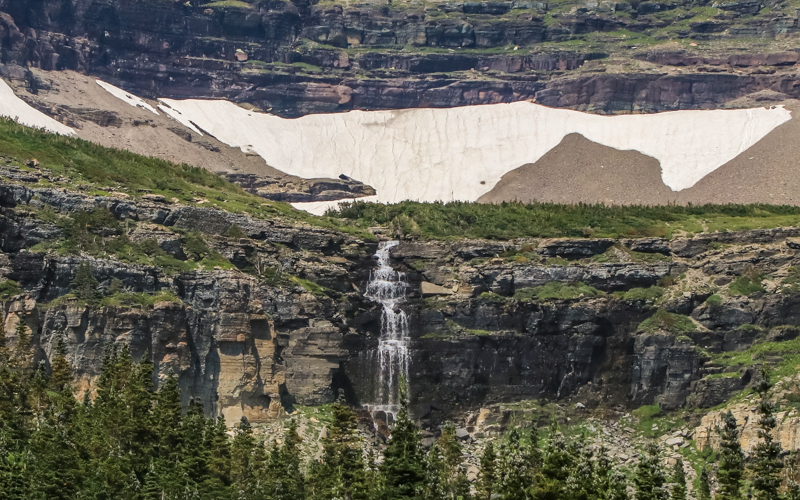 Snow melt cascades over a rock cliff in Glacier National Park