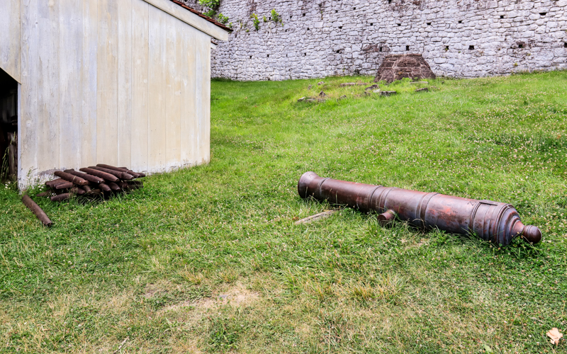 A pile of pig iron bars and a cannon outside of the entrance to the cast house in Hopewell Furnace NHS
