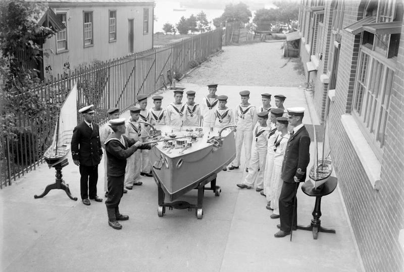 1914-1918 - OUTSIDE THE SEAMANSHIP SCHOOL BOYS UNDER INSTRUCTION WITH PART SHIP MODEL.jpg