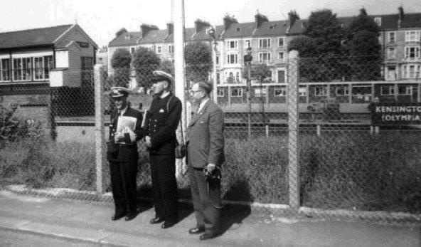 UNDATED - REG FISK, WITH A COMMANDER AND PADRE AT KENISINGTON (OLYMPIA) STATION.jpg