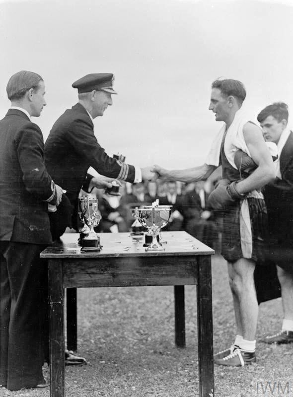 1945, JULY - CDR. WGF SMITHWICK, PRESENTING A BOXING TROPHY AT RNAS HENSTRIDGE, SEE NOTE BELOW.jpg