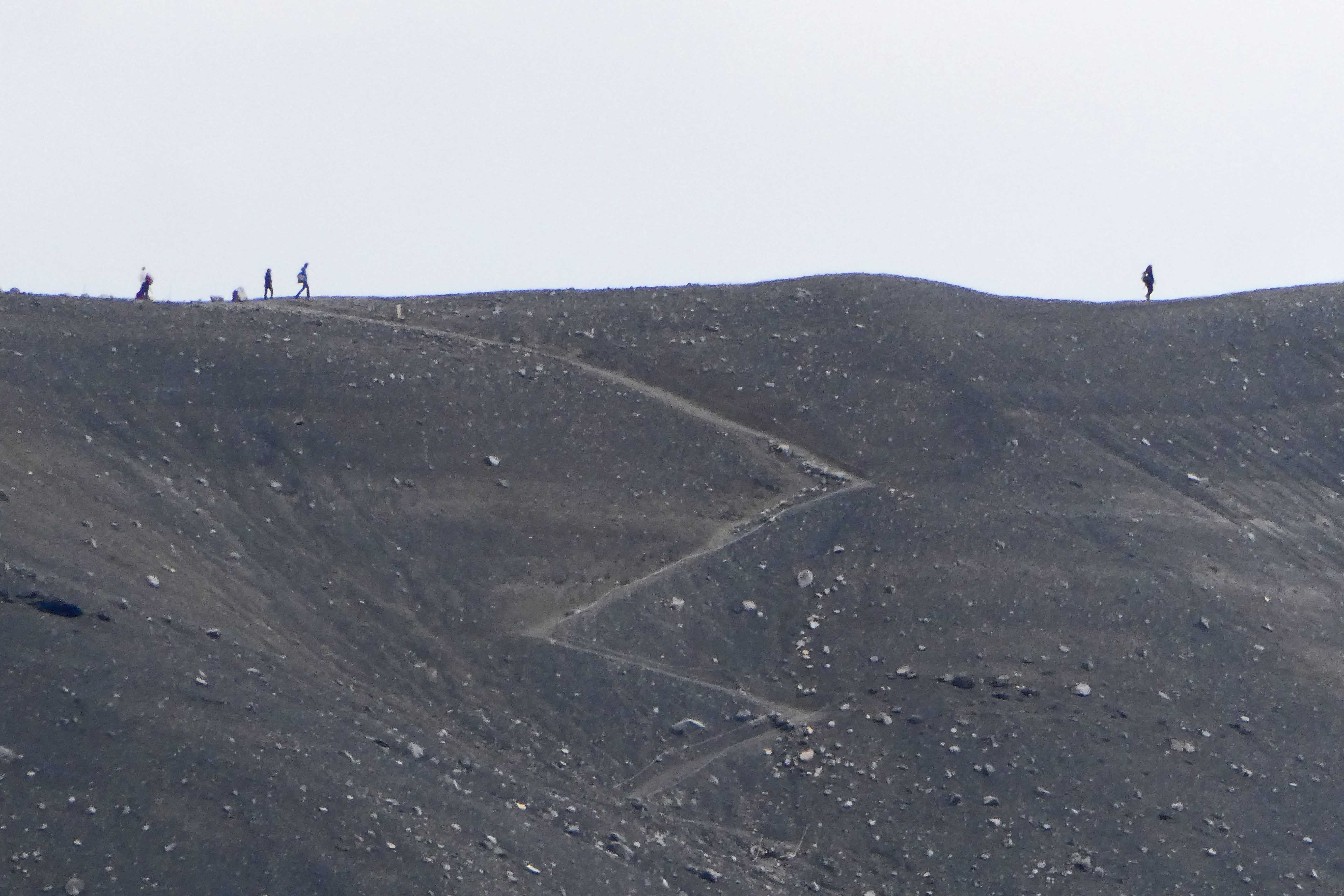 People hiking on the rim of Hverfjall, a crater from a volcano that erupted about 2600 years ago