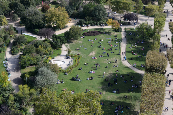 Parisians and tourists enjoying the park at the base of the Eiffel Tower