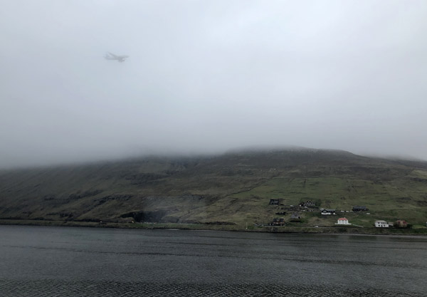 Aircraft landing at Vágar Airport appears through the low clouds, Faroe Islands