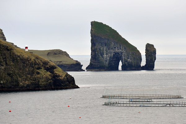 Natural arch through the island of Drangarnir with a fish farm