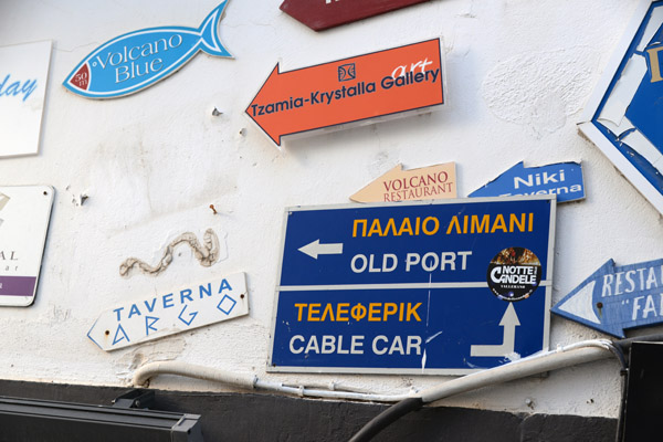 Signs for restaurants and the Old Port and Cable Car, Fira