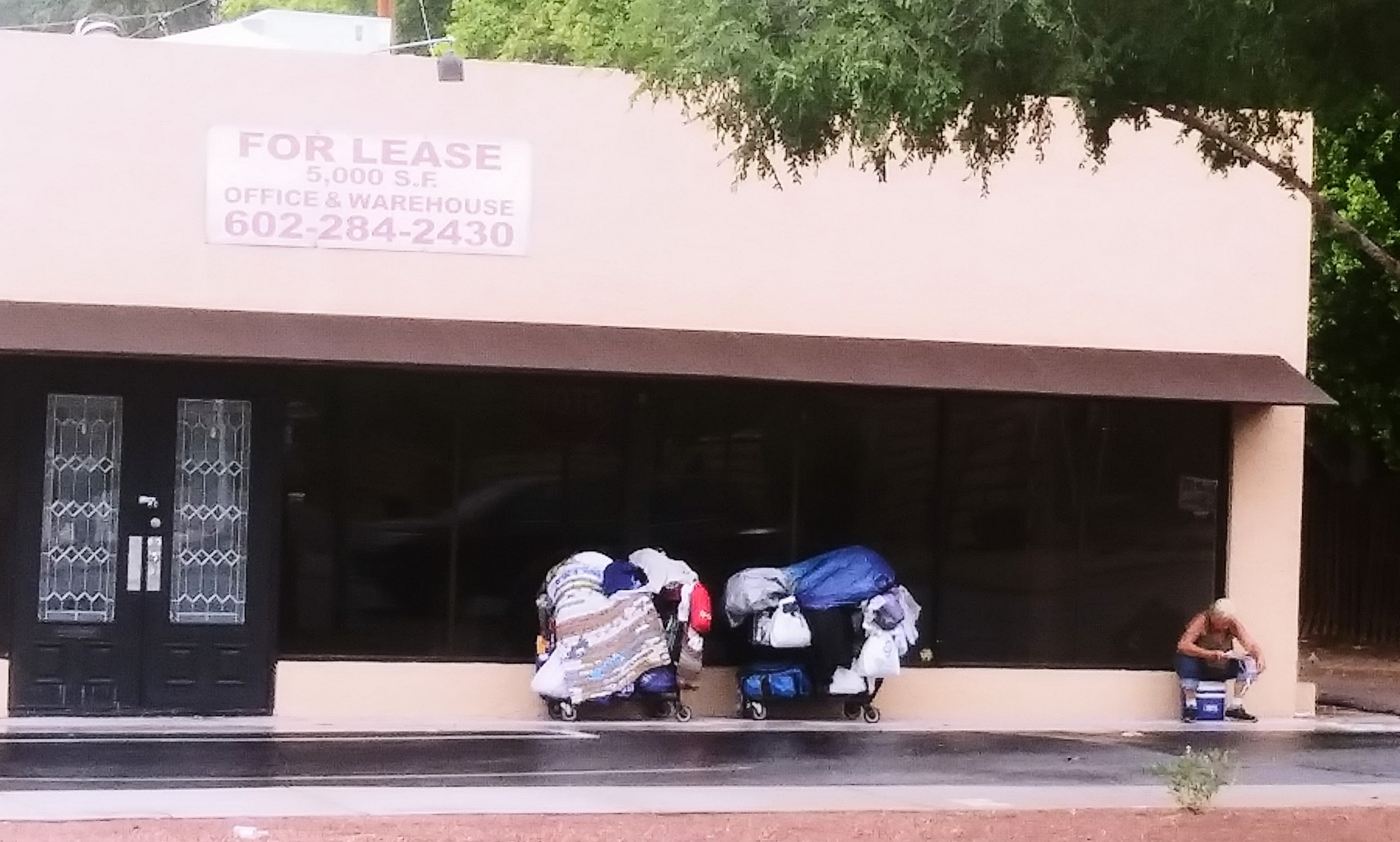 Senior homeless woman in front of empty store been For Lease for months