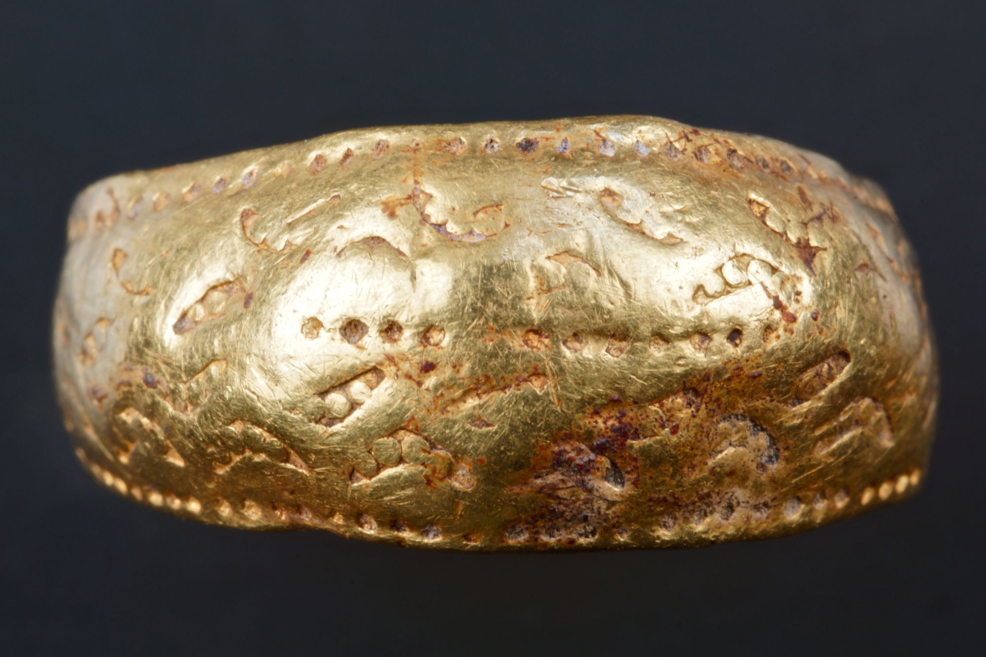 Viking Age ring with stamped decoration. There are three lines of diamonds and four lines of lunate forms with pellets.