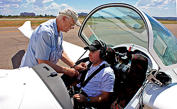 Ted readies Guy Schmickle for flight while Guy says his prayers.