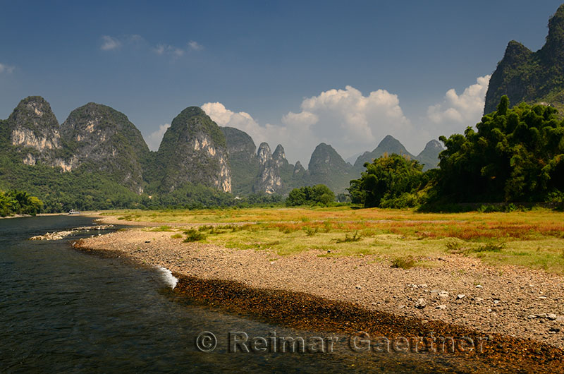Pebble shore of the Lijiang River China with pointed Karst cones and peaks