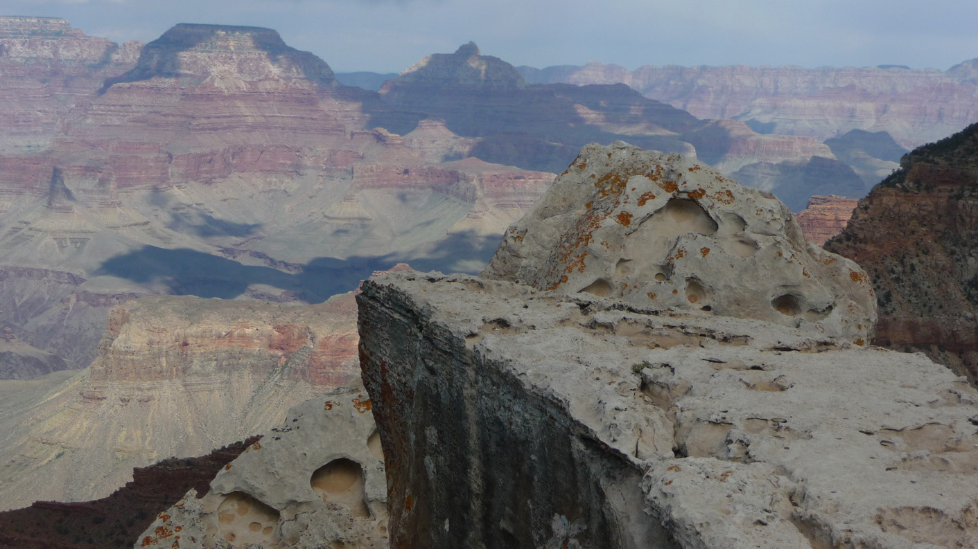 View of a sheer cliff with interesting rock formations in the background.