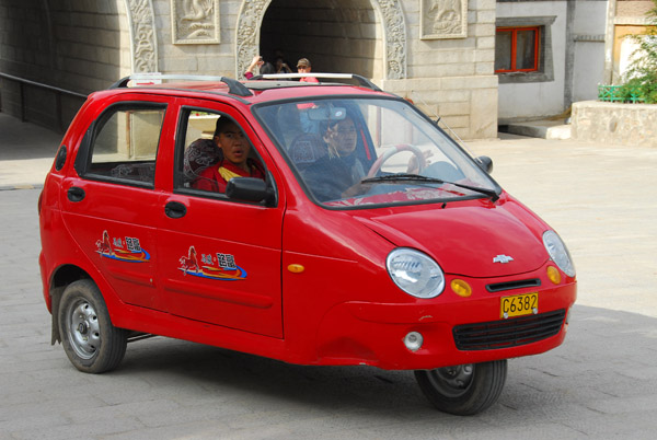 Monk arriving in an odd 3-wheeled car