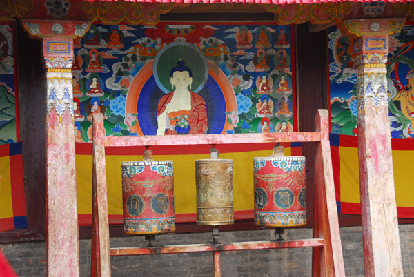 Prayer wheels and a Thangka painting of the Sakyamuni Buddha