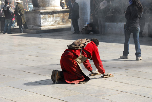 Tibetan pilgrim prostrating in front of the Jokhang, Barkhor Square