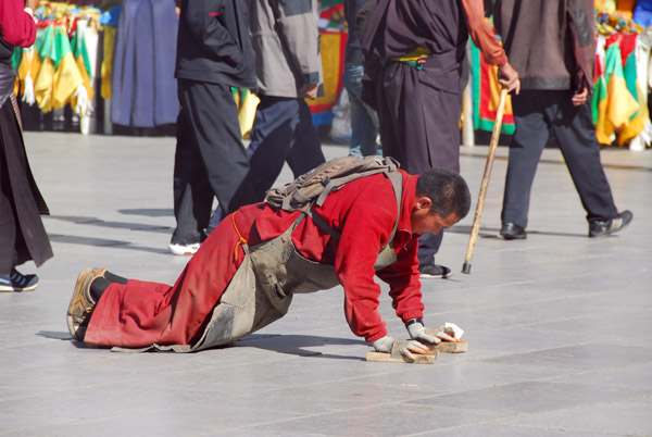 Tibetan pilgrim prostrating in front of the Jokhang, Barkhor Square