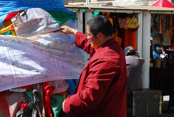 Well fed monk inspecting prayer flags