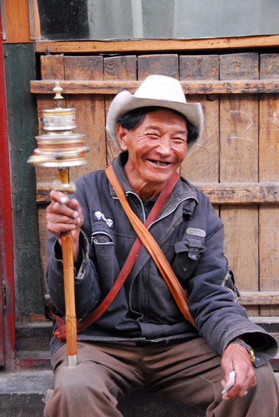 Smiling Tibetan man spinning a prayer wheel